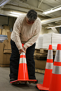 [Image Description: A person lifting an orange traffic cone]