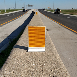 [Image Description: A Flex-O-Matic Delineator mounted on top of a concrete barrier dividing two lanes of traffic.]
