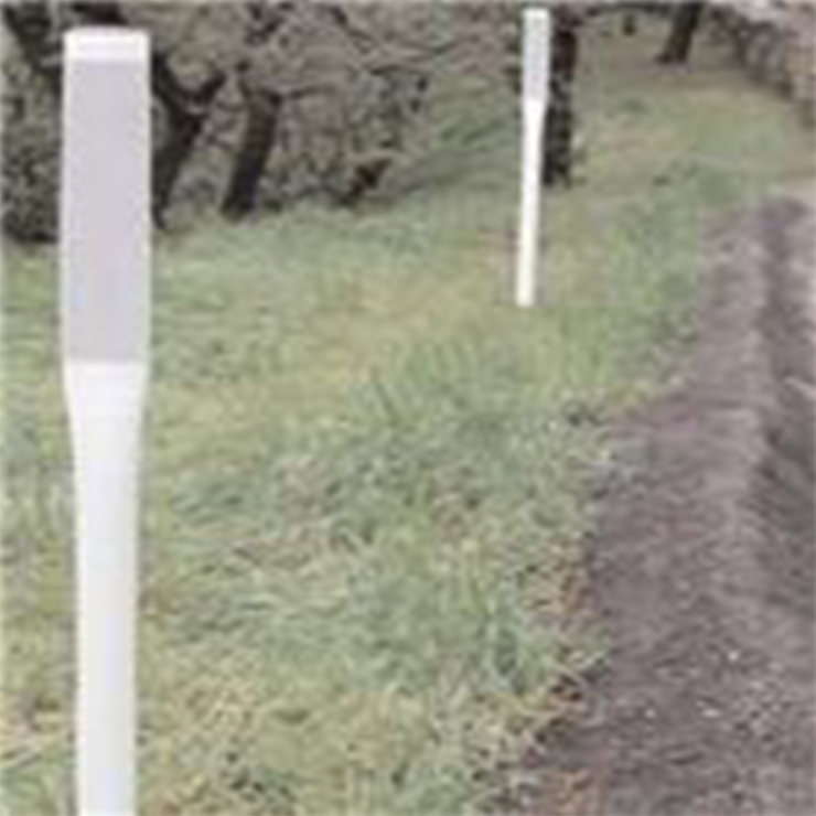 [Image Description: A row of white pole style delineators lined up on a grass.]